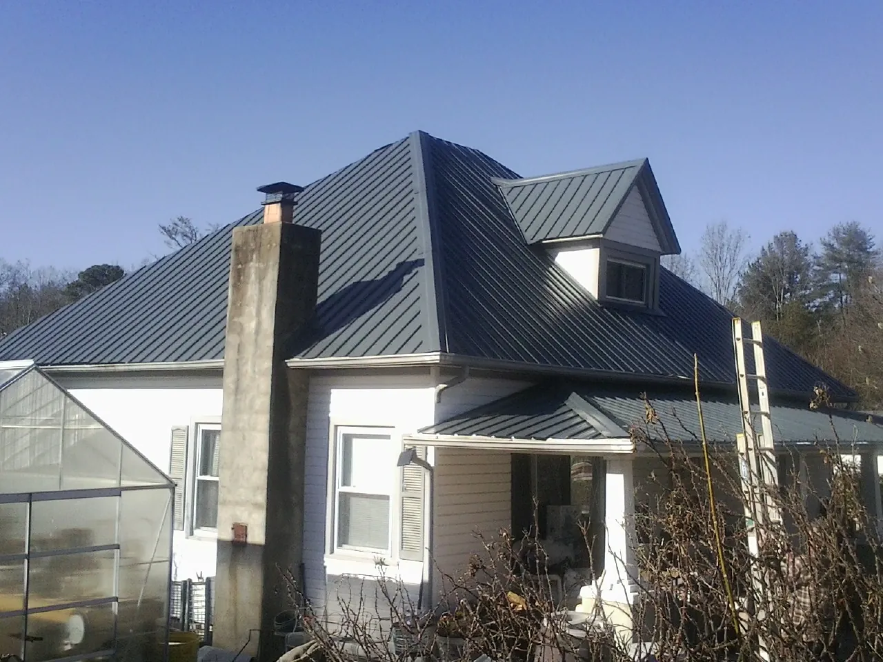 Dark blue standing seam metal roof on a white farmhouse with dormer — Slate & Tile Roof Repair by Roofing Brothers in Tieton