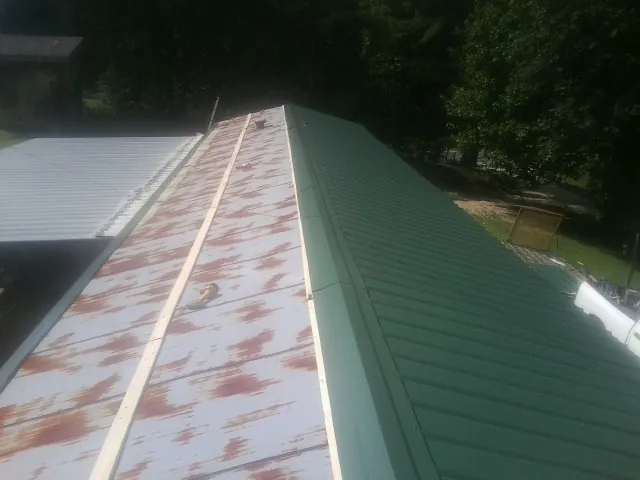 Old rusted panels beside newly installed green metal roofing — Wind Damage Roof Repair by Roofing Brothers in Tieton