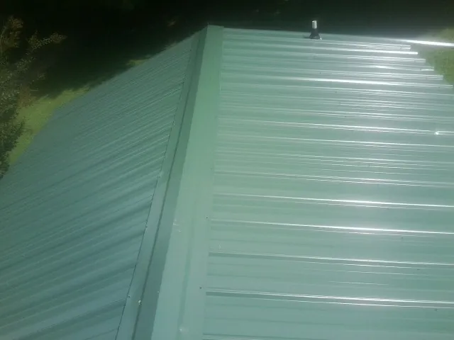 New green metal panels meeting at the ridge of a roof — Flat Roof Repair work by our crew in Tieton