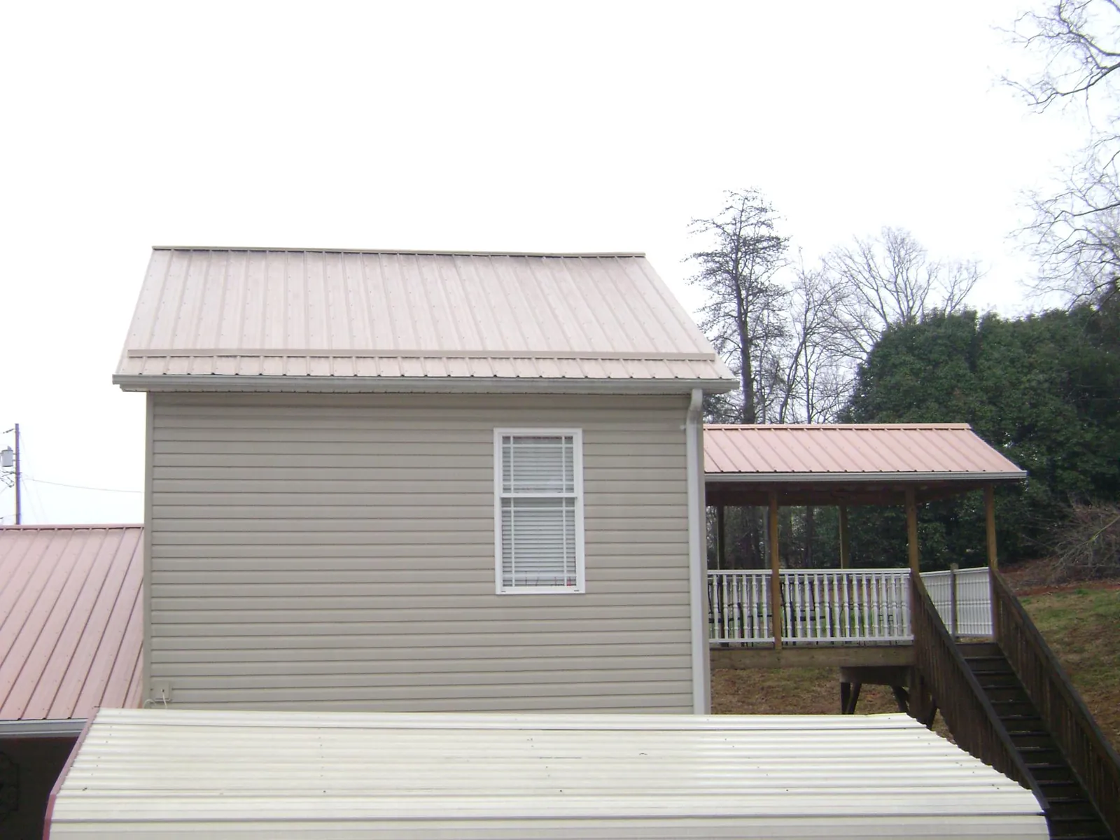 Tan metal roofs on a two story addition and attached porch, from a Roof Replacement job in Tieton