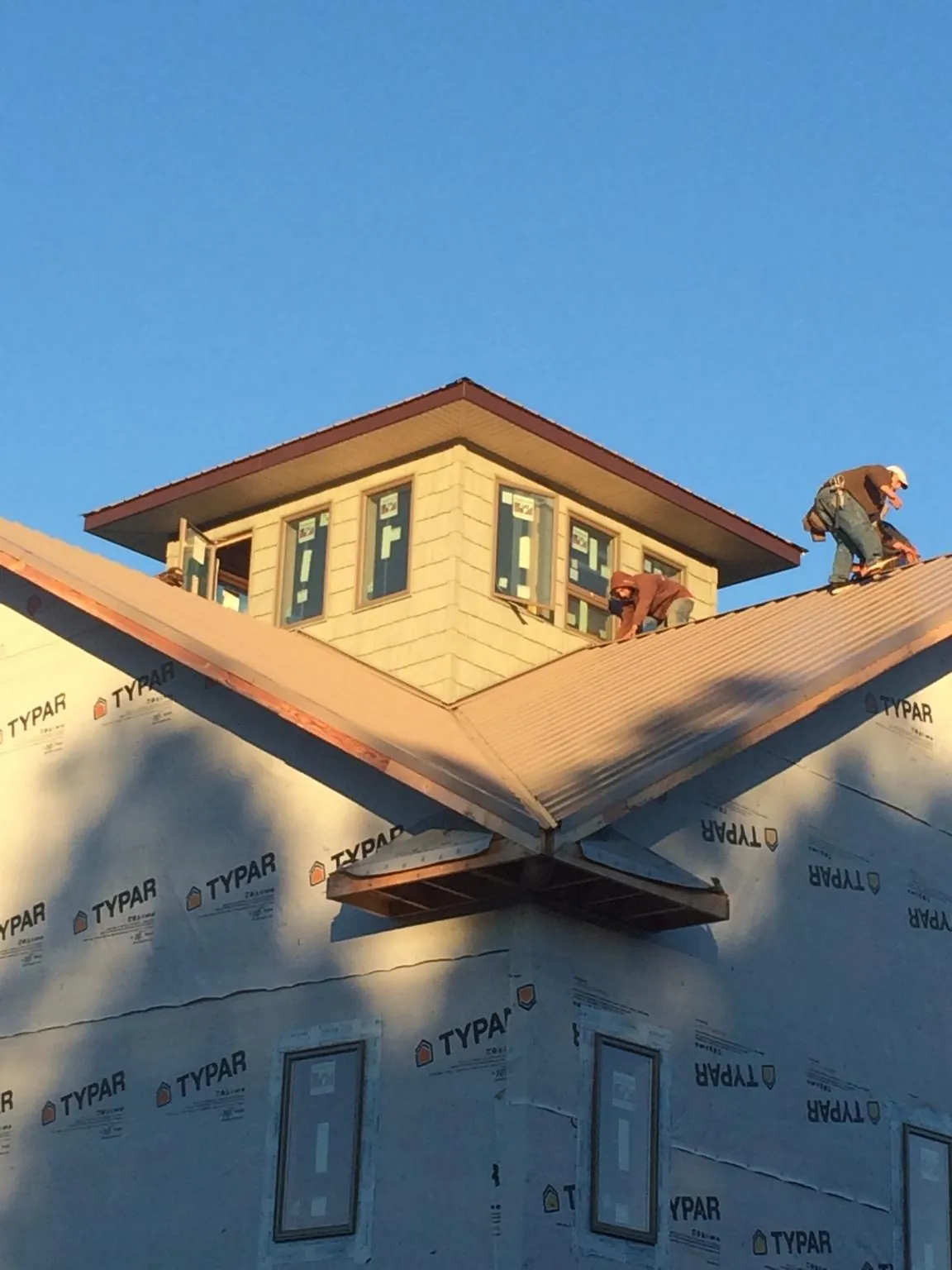 Roofers working around a rooftop cupola on a new metal roof at sunset — Roof Waterproofing in Tieton by Roofing Brothers